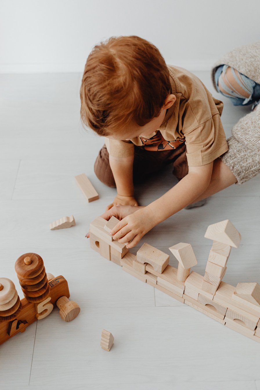 Kid in a Brown Shirt Playing with Wooden Building Blocks