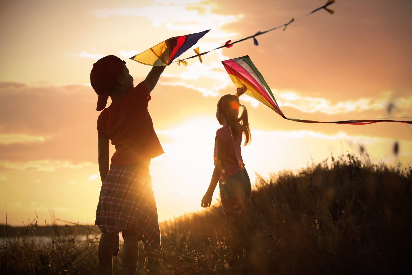 Little Children Playing with Kites Outdoors at Sunset. Spending