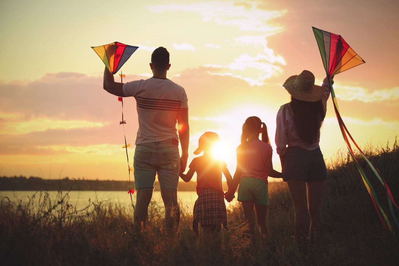 Parents and Their Children Playing with Kites Outdoors at Sunset